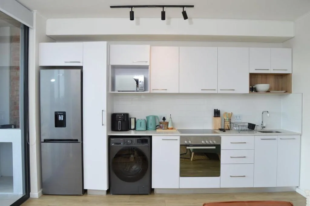 Modern kitchen with white cabinetry, stainless steel appliances, and marble countertop