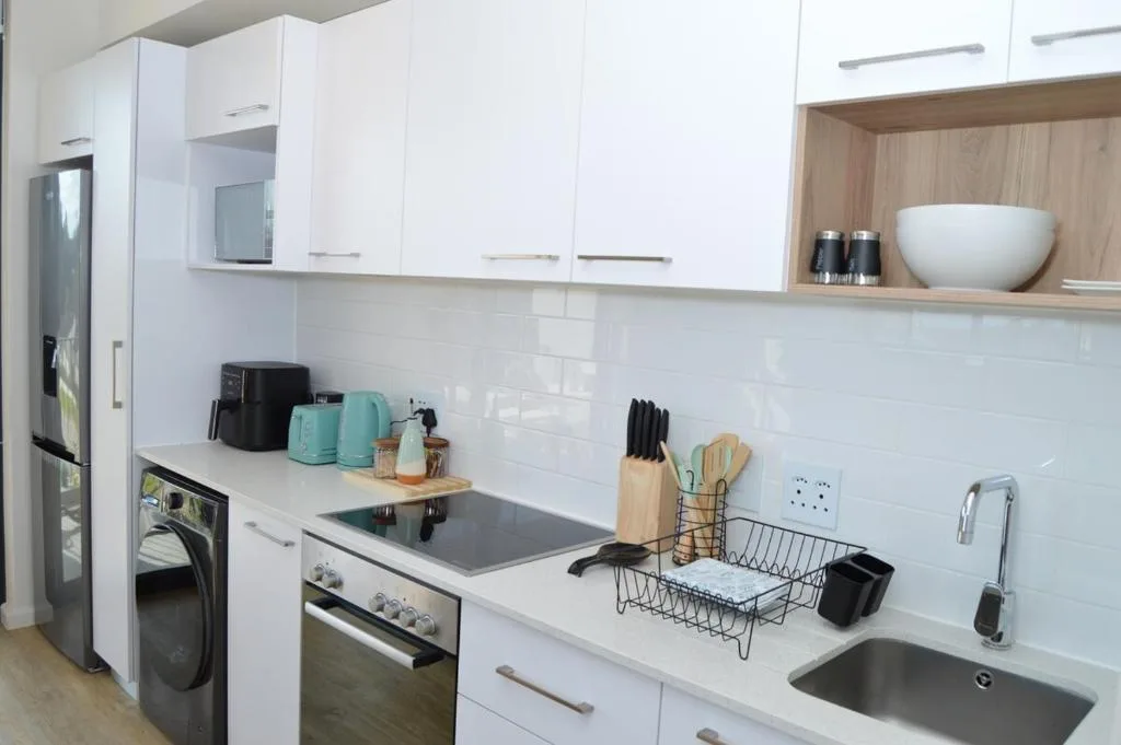 Modern white kitchen with stove, sink, and stainless steel appliances