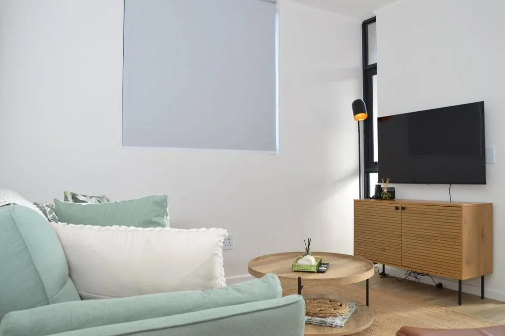 Modern living room with mint green sofa, wooden TV console, and wall art