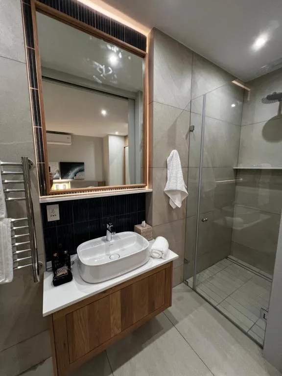 Modern bathroom with oval sink, large mirror, and glass shower enclosure