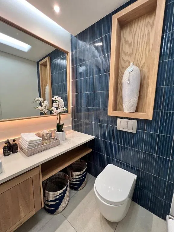 Modern bathroom with dark tile walls, wooden vanity, and contemporary fixtures