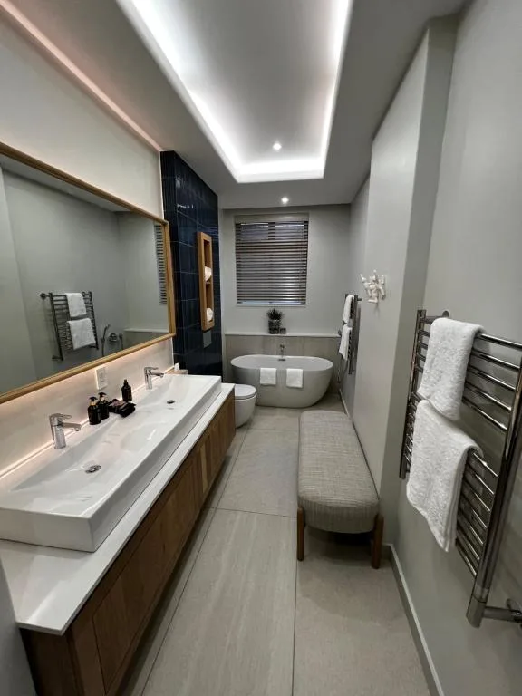 Modern bathroom with double vanity, freestanding bathtub, heated towel rack