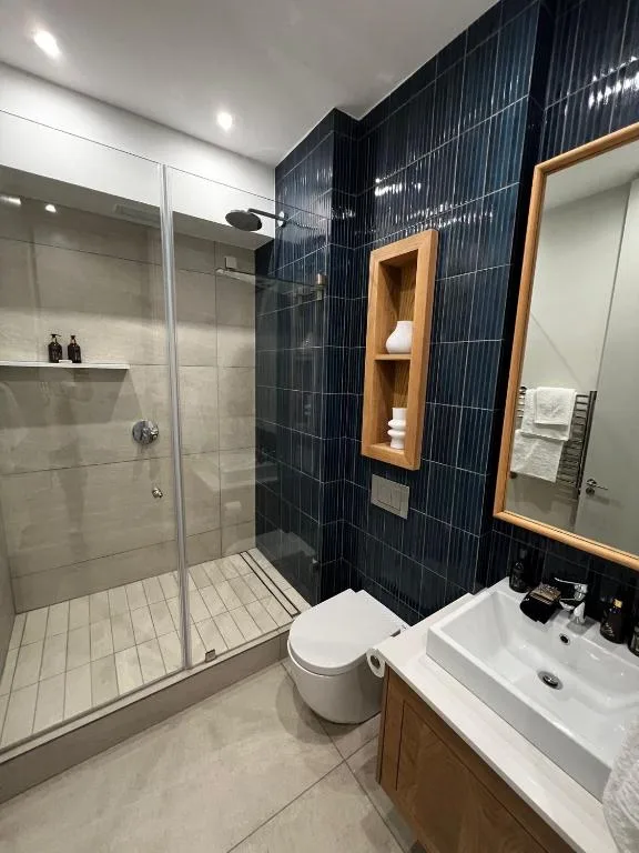 Modern bathroom with walk-in shower, vanity sink, and wooden accents