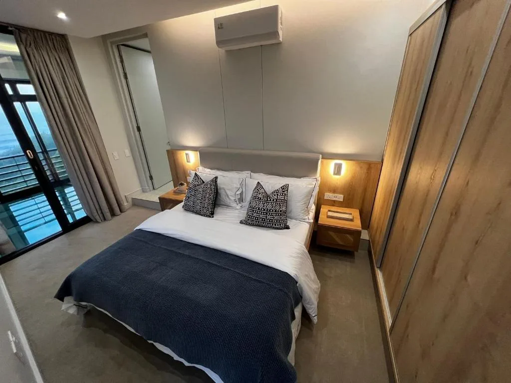 Modern bedroom with queen bed, patterned pillows, and warm bedside lighting