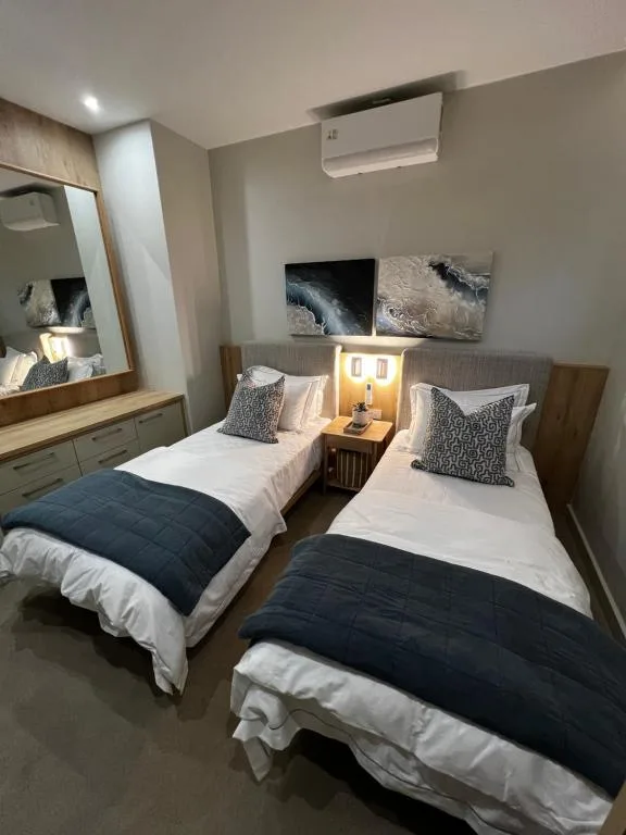Twin beds with white linens and dark navy throws in modern bedroom