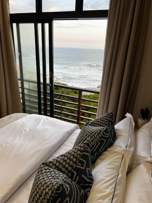 Bedroom with ocean view through glass doors and balcony railing