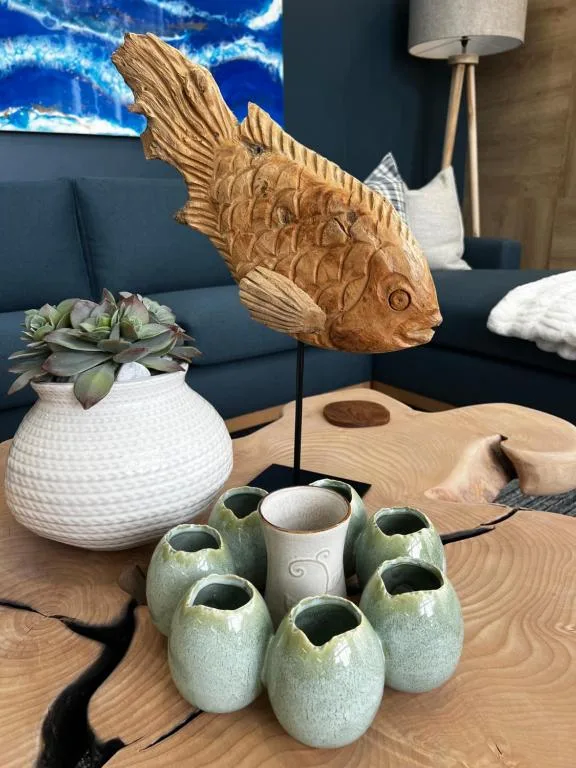 Wooden fish sculpture with succulent plant and ceramic vases on table