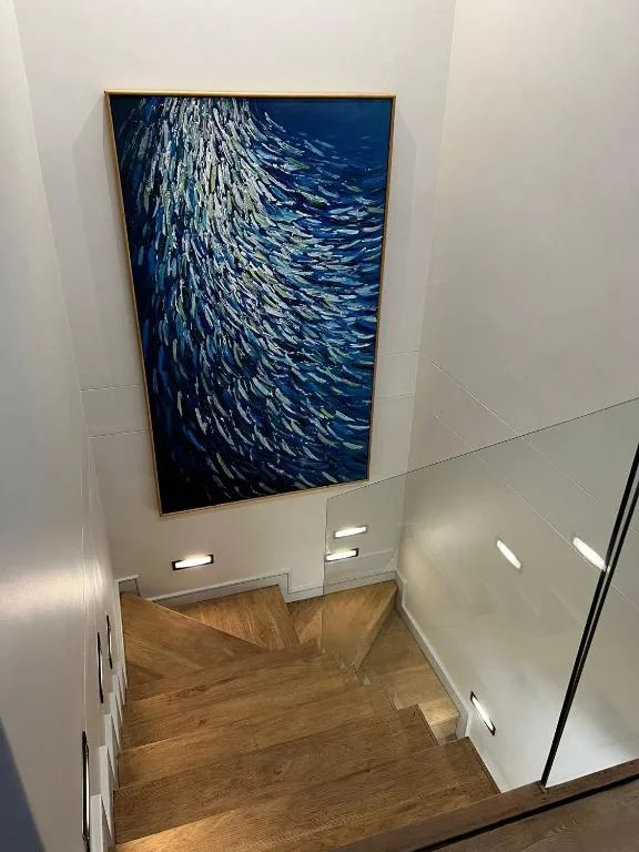 Modern staircase with wooden treads and framed ocean wave artwork on wall