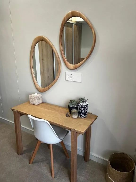 Wooden vanity desk with two oval mirrors and decorative accessories