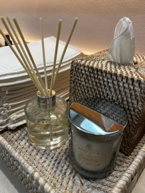 Decorative reed diffuser and scented candle on woven table surface