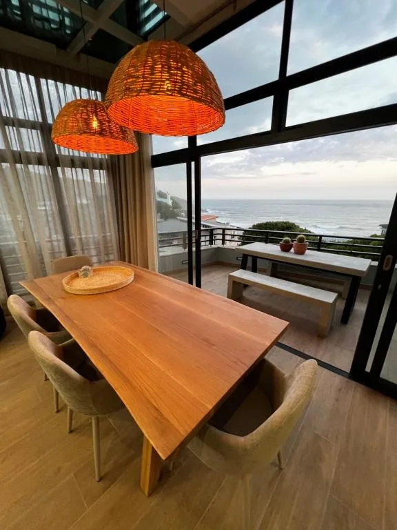 Dining area with wooden table, wicker pendant lights, ocean view