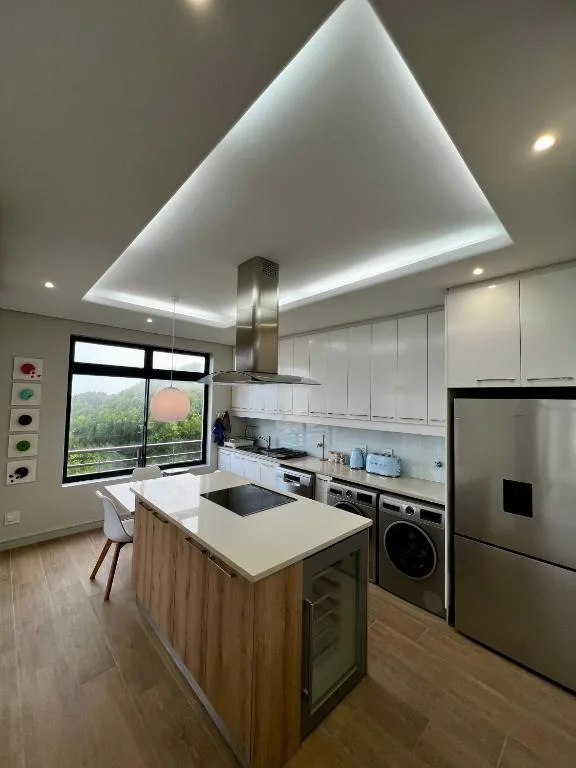 Modern kitchen with island, stainless steel appliances, and LED ceiling lighting