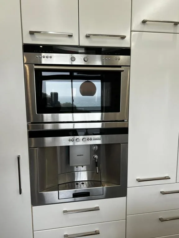 Stainless steel built-in oven and coffee machine with white cabinetry