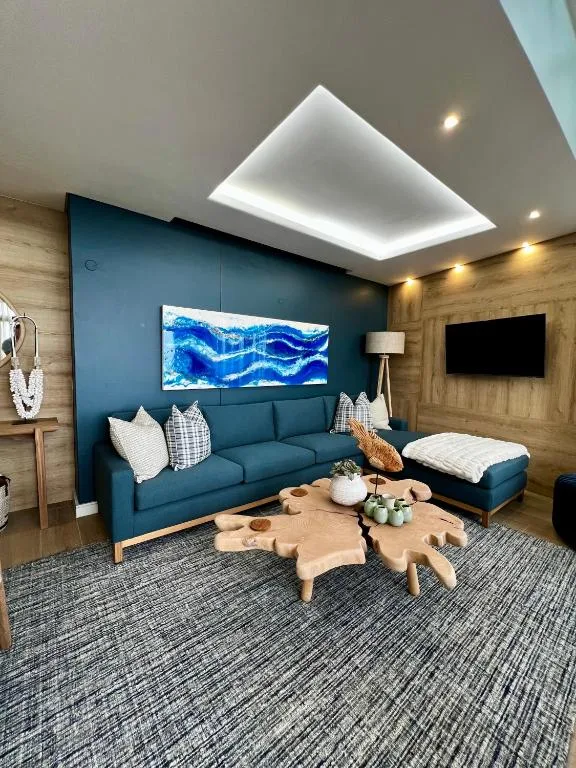 Modern lounge with teal sofa, wooden accents, and skylight ceiling