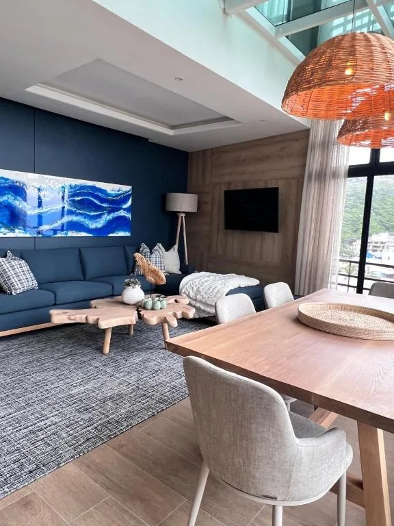 Modern lounge with blue sofa, dining table, and ocean view window