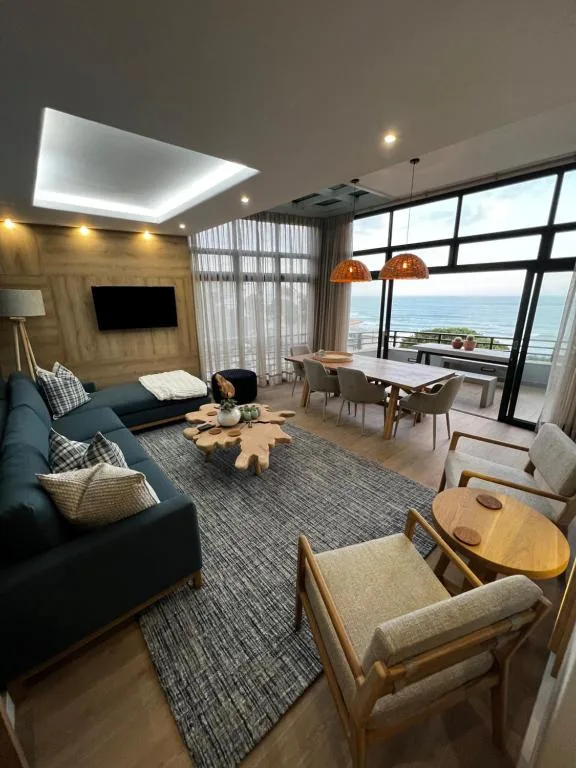 Modern penthouse lounge with ocean view, sofa, and dining area