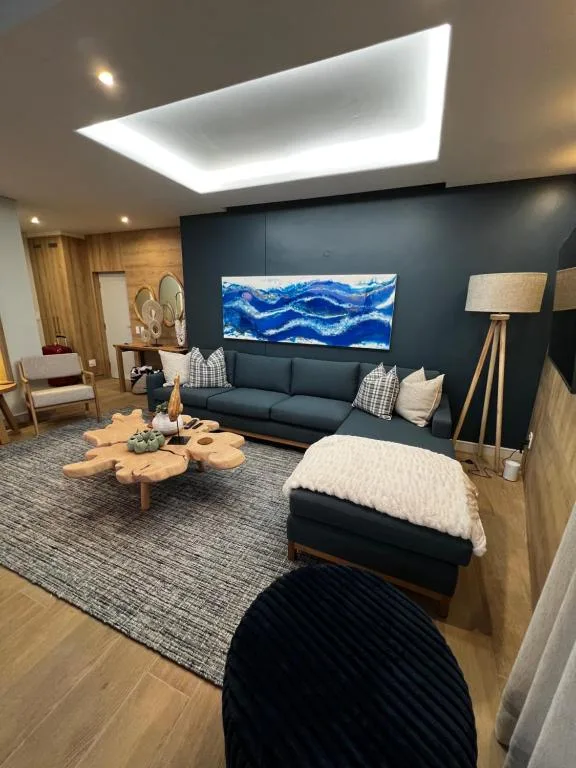 Modern lounge with dark sofa, geometric ceiling light, and blue artwork