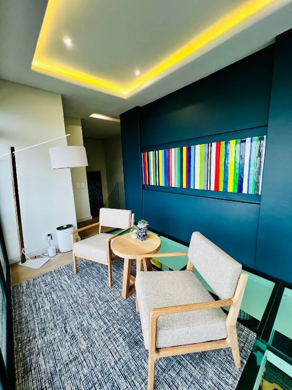 Modern lounge with teal accent wall, comfortable seating, and ambient ceiling lighting