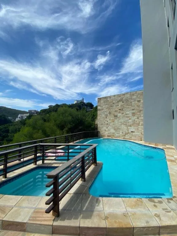 Bright turquoise swimming pool on elevated deck with mountain views and blue sky