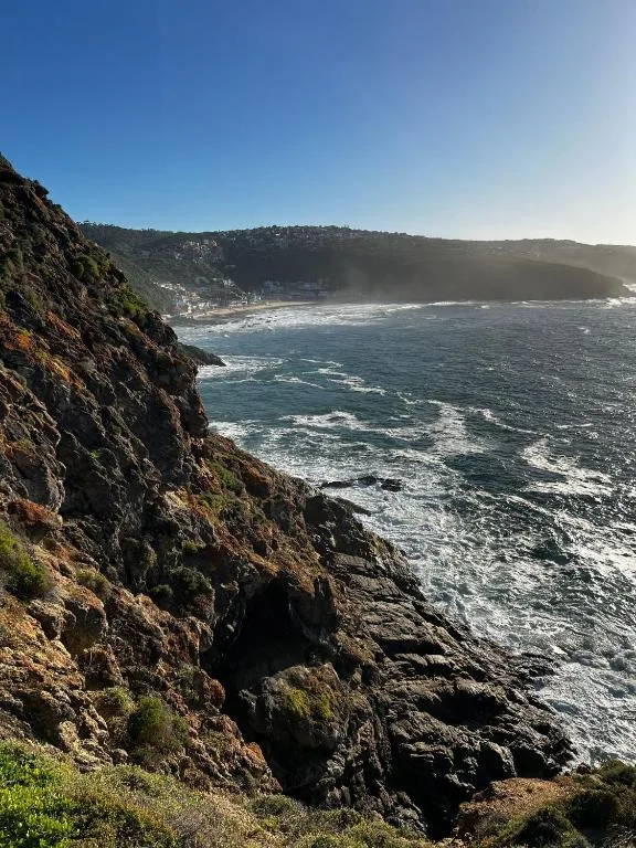 Dramatic coastal cliffs overlooking turquoise ocean waves and sandy beach