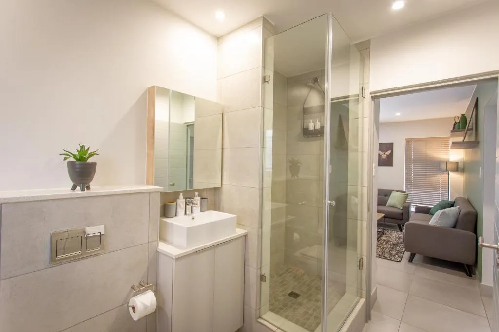 Modern bathroom with walk-in shower, white vanity, and potted succulent plant
