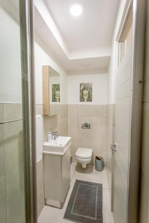 Clean modern bathroom with vanity, toilet, and tiled walls