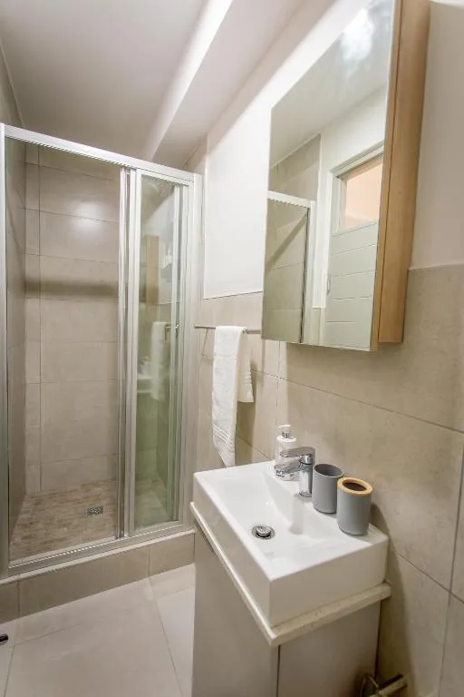 Modern bathroom with walk-in shower, white vanity sink, and mirror cabinet