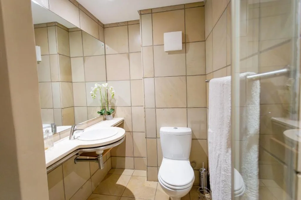 Modern bathroom with vanity sink, toilet, and shower enclosure with towels