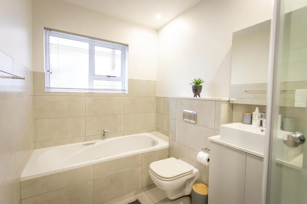 Clean bathroom with bathtub, toilet, sink, and beige tile walls