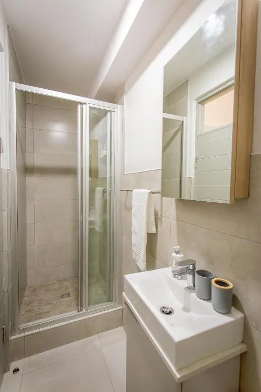 Modern bathroom with shower enclosure, white vanity sink, and mirror
