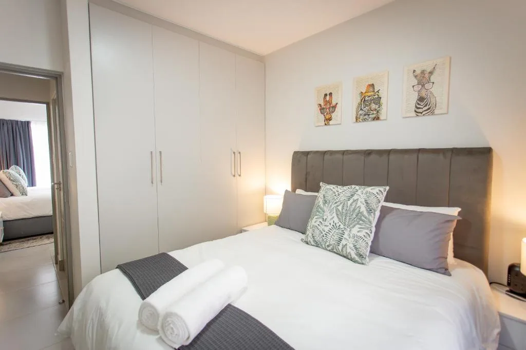 Modern bedroom with grey upholstered headboard and white built-in wardrobes