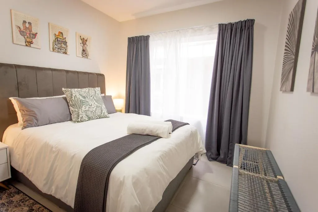 Spacious bedroom with upholstered headboard, white bedding, and gray curtains