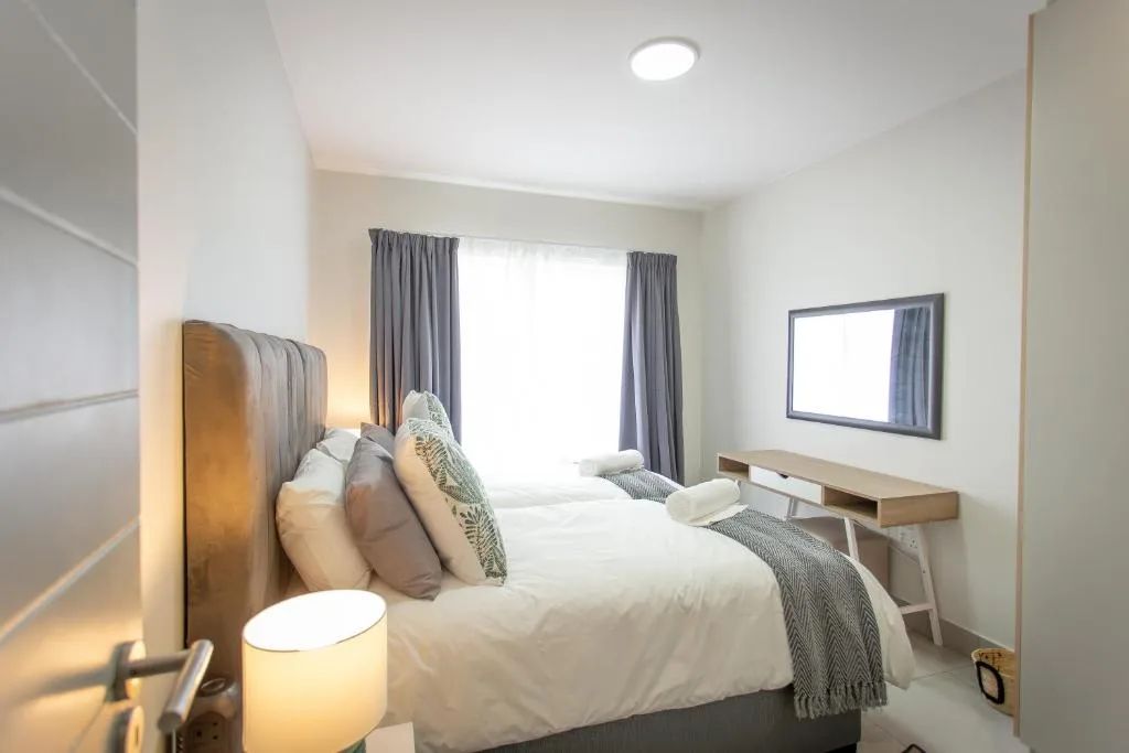 Spacious modern bedroom with queen bed, grey curtains, and flat-screen TV