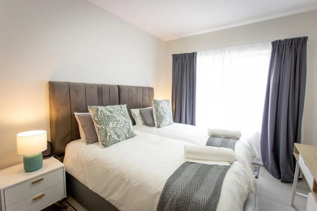 Contemporary bedroom with twin beds, upholstered headboard, and large windows
