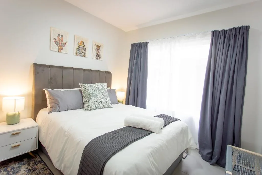 Bright bedroom with upholstered headboard, white bedding, and grey curtains