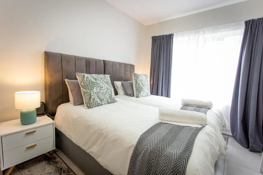 Spacious bedroom with twin beds, upholstered headboard, and natural light