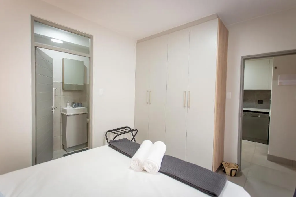 Modern bedroom with white bed, built-in wardrobe, and ensuite bathroom access