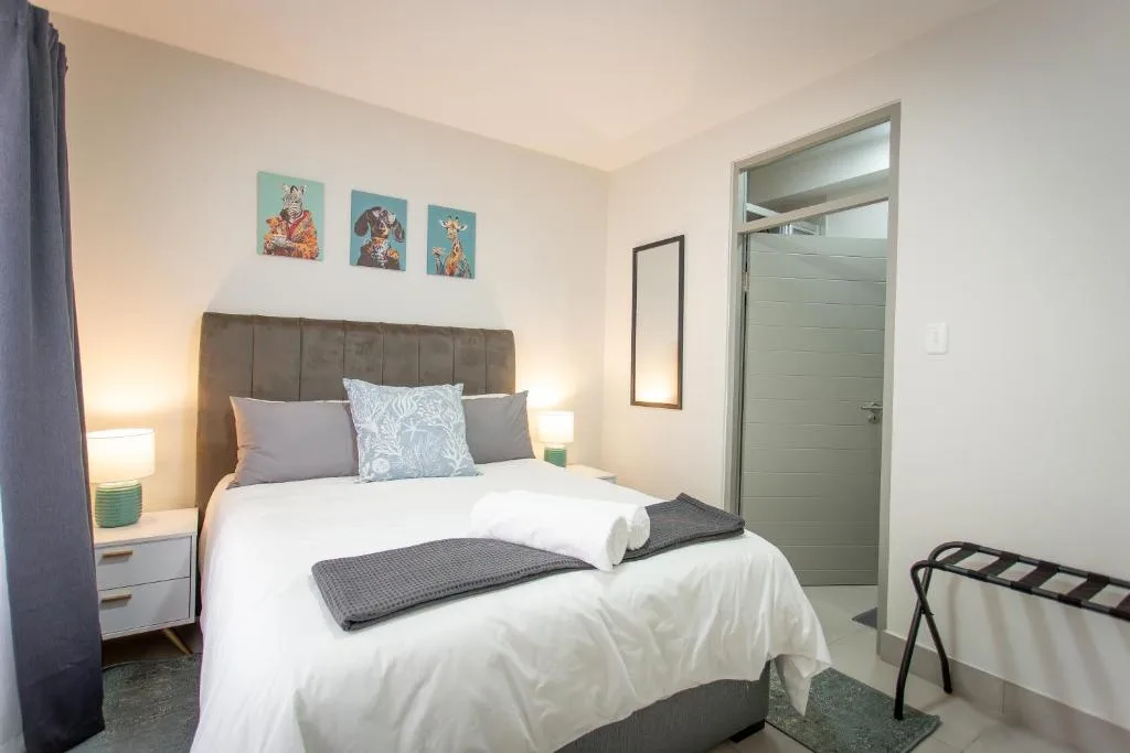 Spacious bedroom with upholstered headboard, white bedding, and colorful wall art