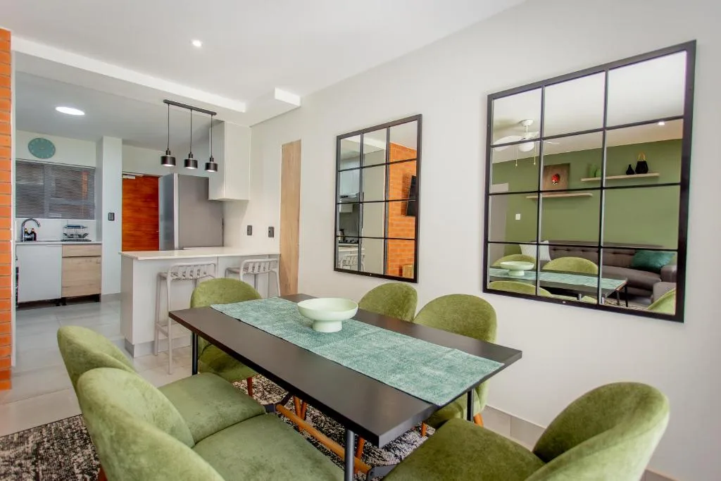 Modern dining area with green chairs and gray table near kitchen