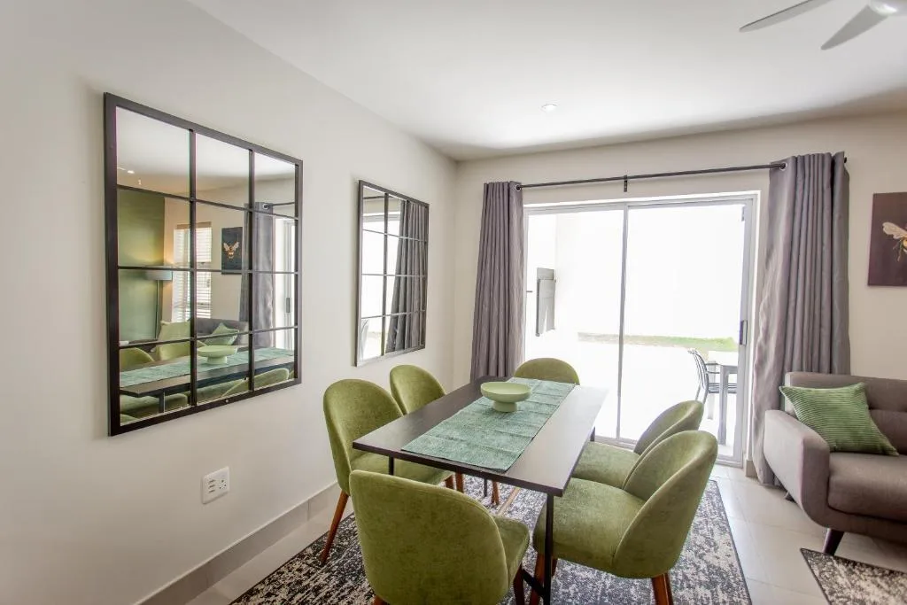 Modern dining table with green chairs and sliding glass door access to deck