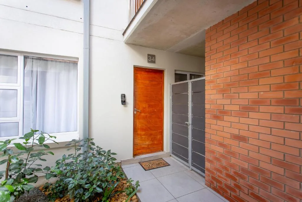 Modern apartment entrance with orange wooden door and brick facade