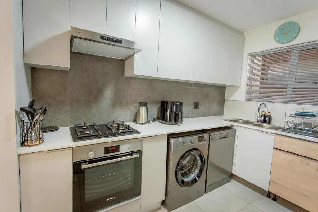 Modern kitchen with white cabinetry, gas stove, oven, and washing machine