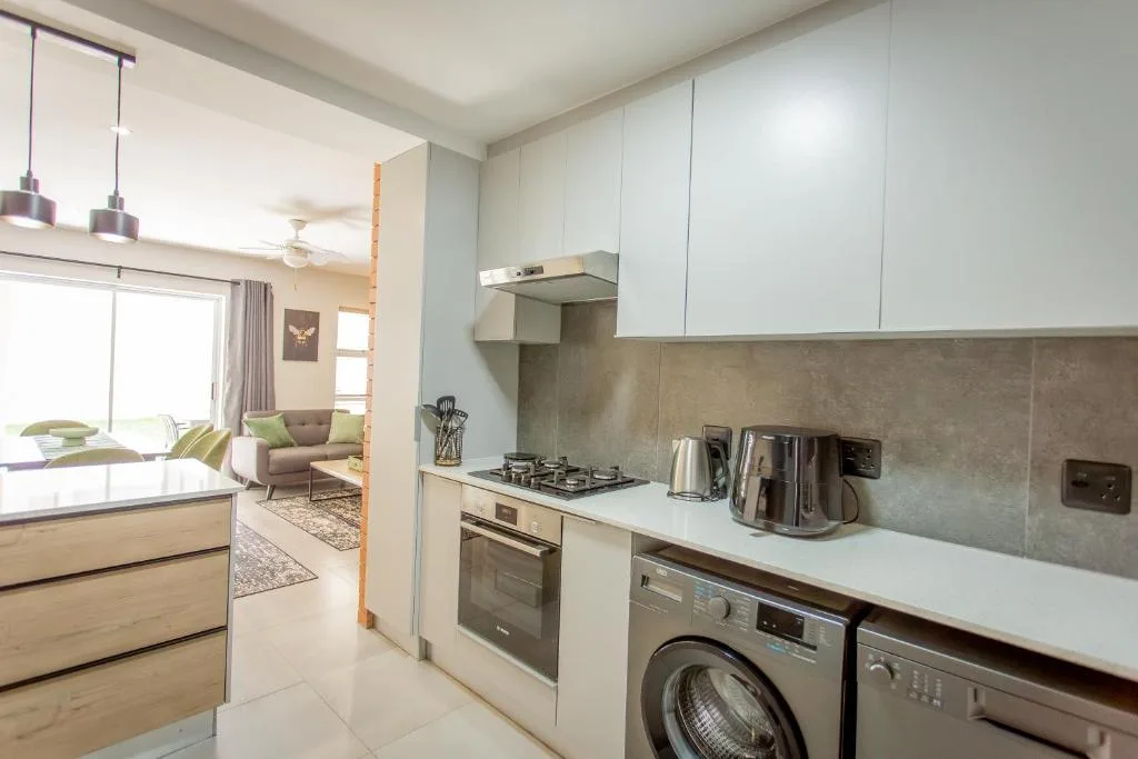 Modern kitchen with stove, oven, washing machine, and white cabinetry