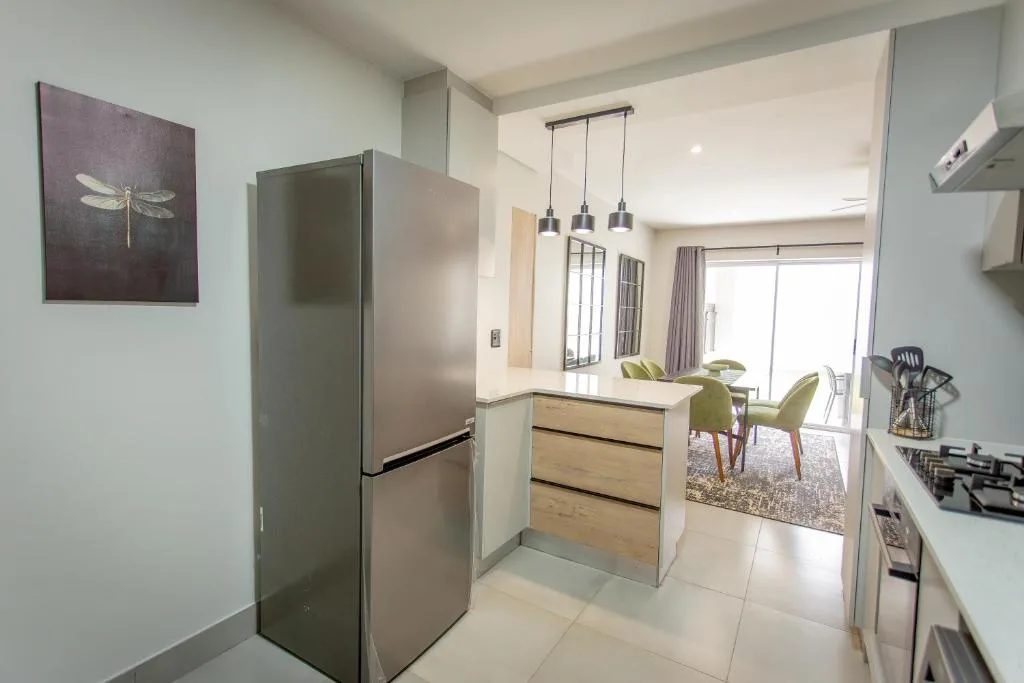 Modern kitchen with stainless steel fridge, gas cooktop, pendant lighting, and island counter