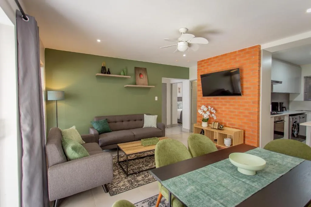 Modern lounge with gray sofa, green accent wall, and wall-mounted television