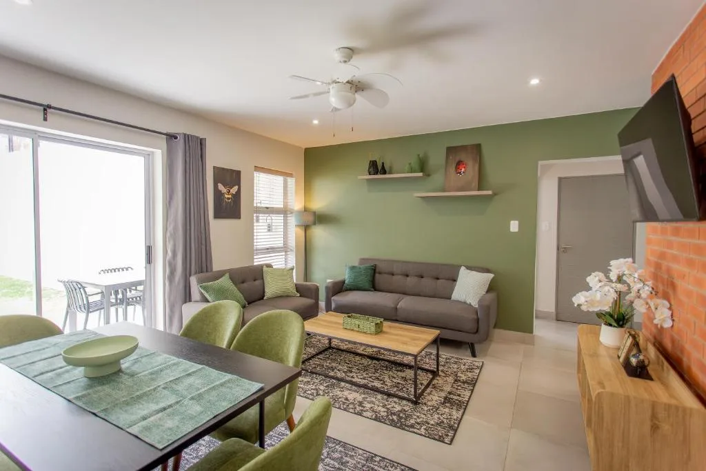 Modern lounge with gray sofa, green accent wall, and open dining area