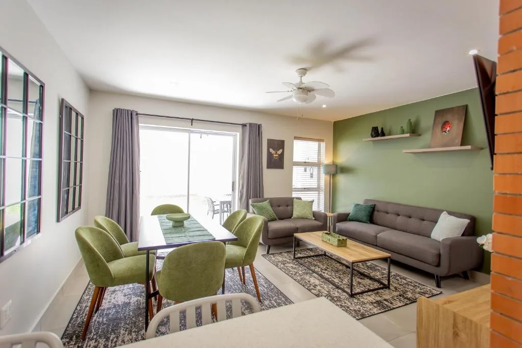 Modern lounge with gray sofa, green accent chairs, and deck access