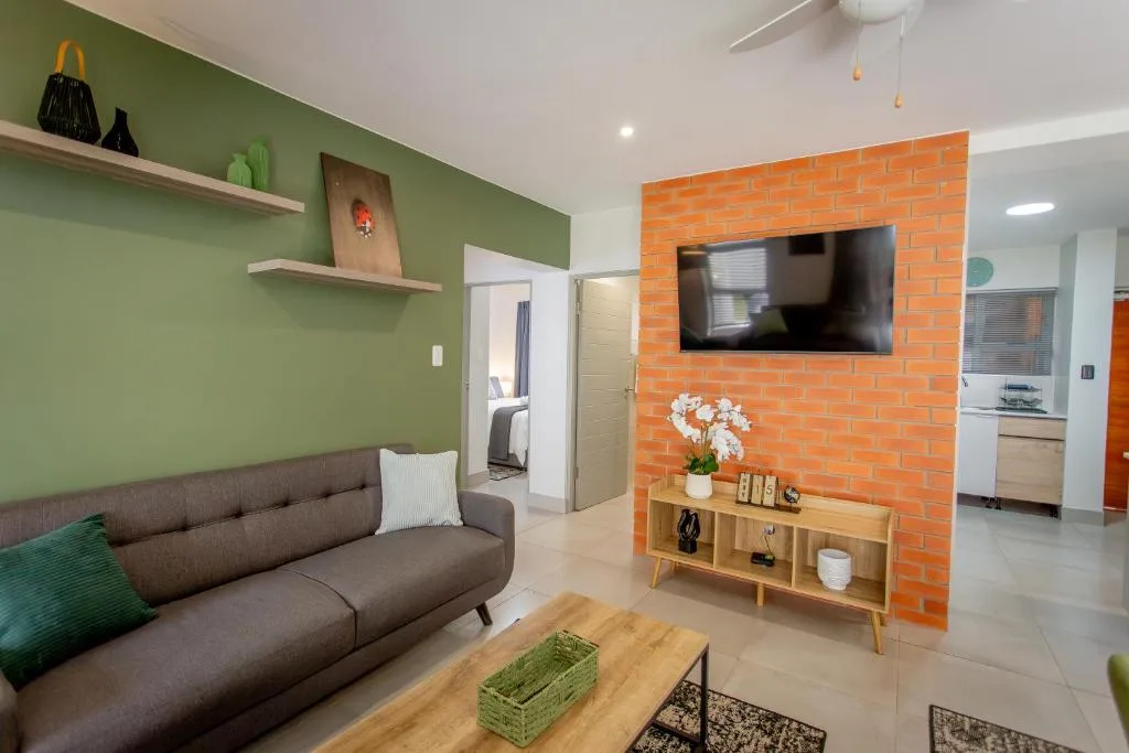 Modern lounge with gray sofa, green accent wall, and mounted television
