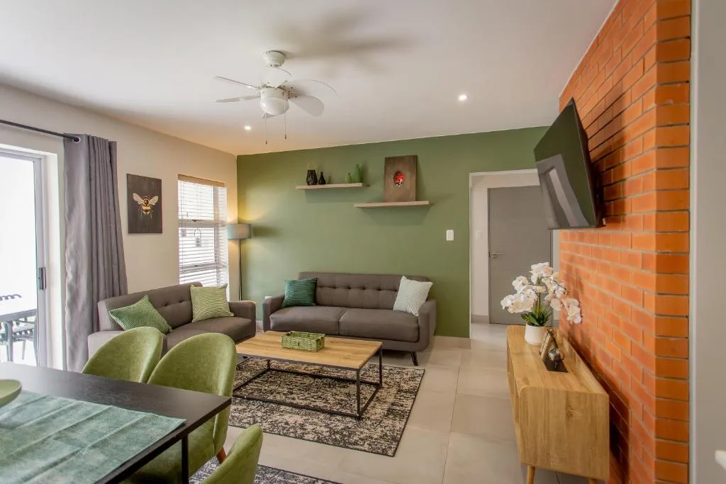 Modern lounge with green accent wall, gray sofa, and brick fireplace