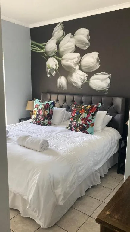Bedroom with queen bed, dark headboard, white linens, floral wall art